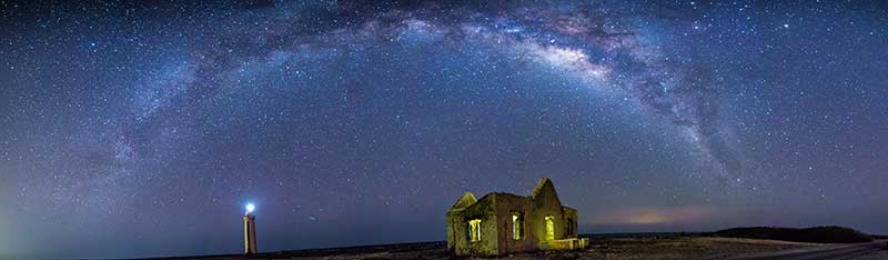 Panoramic view of Bonaire's Willemstoren Lighthouse and Keeper's House under the Milky Way.